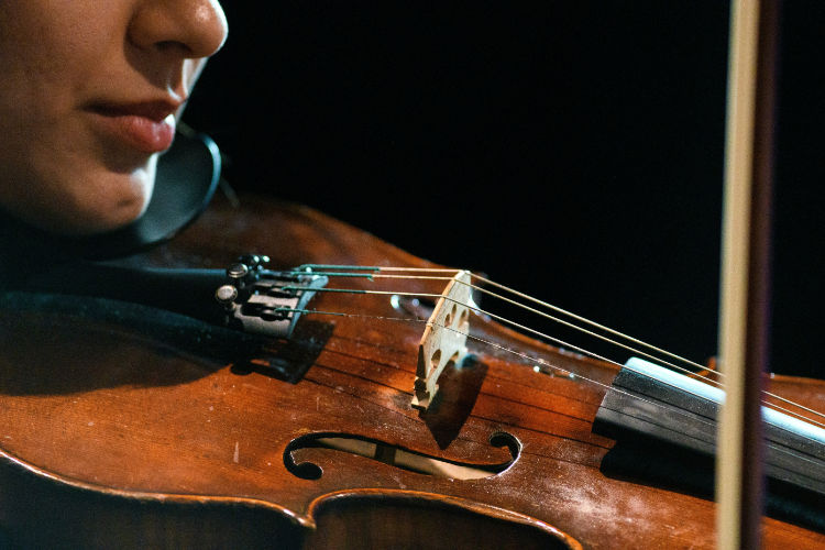 violin with bow on dark wooden surface, classical music, elegant close-up, soft dramatic lighting