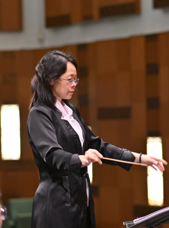 elegant female violinist and conductor in evening gown holding a violin, poised portrait, warm stage
