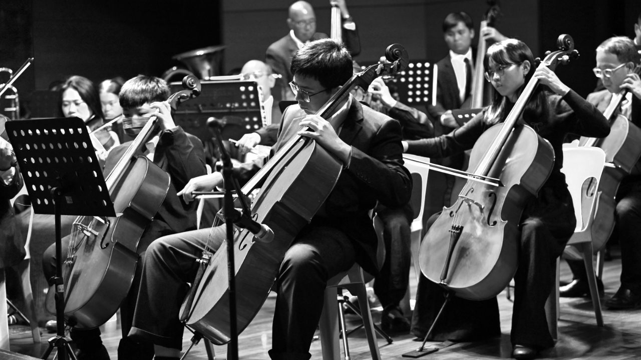 historical black and white photograph of a young orchestra conducting rehearsal in a classic Europea