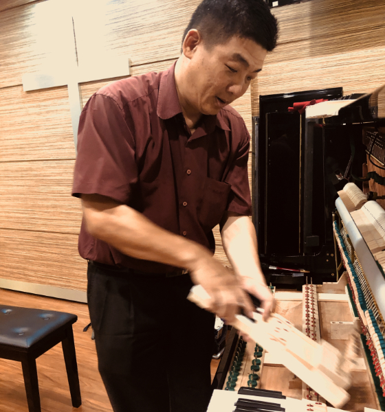portrait of a professional piano technician tuning a grand piano, focused expression, holding a tuni